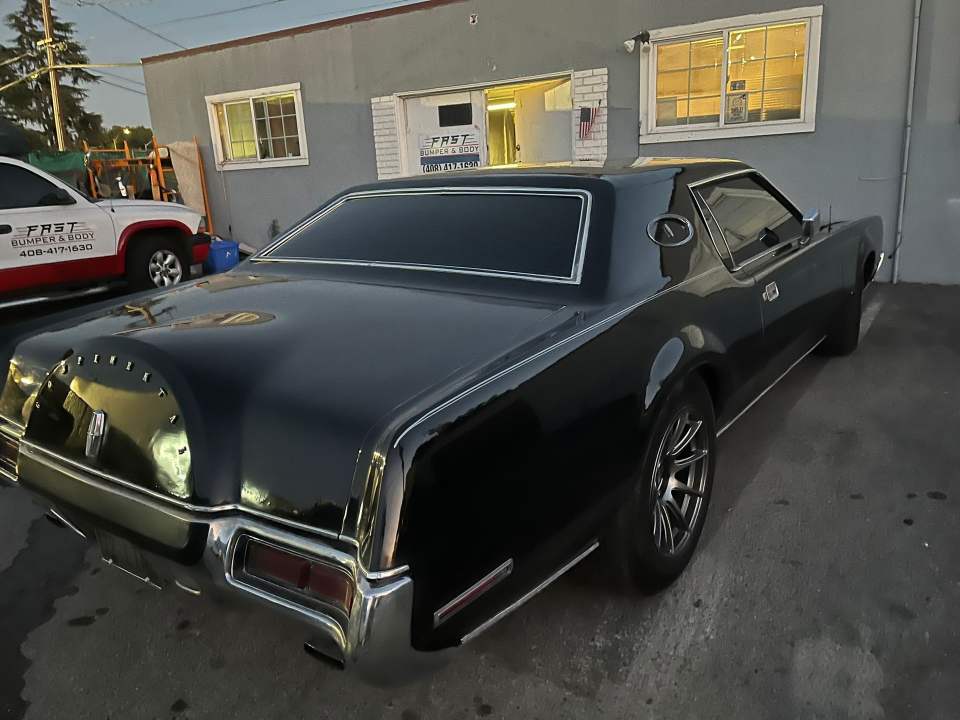 Black classic car parked outside a building at dusk