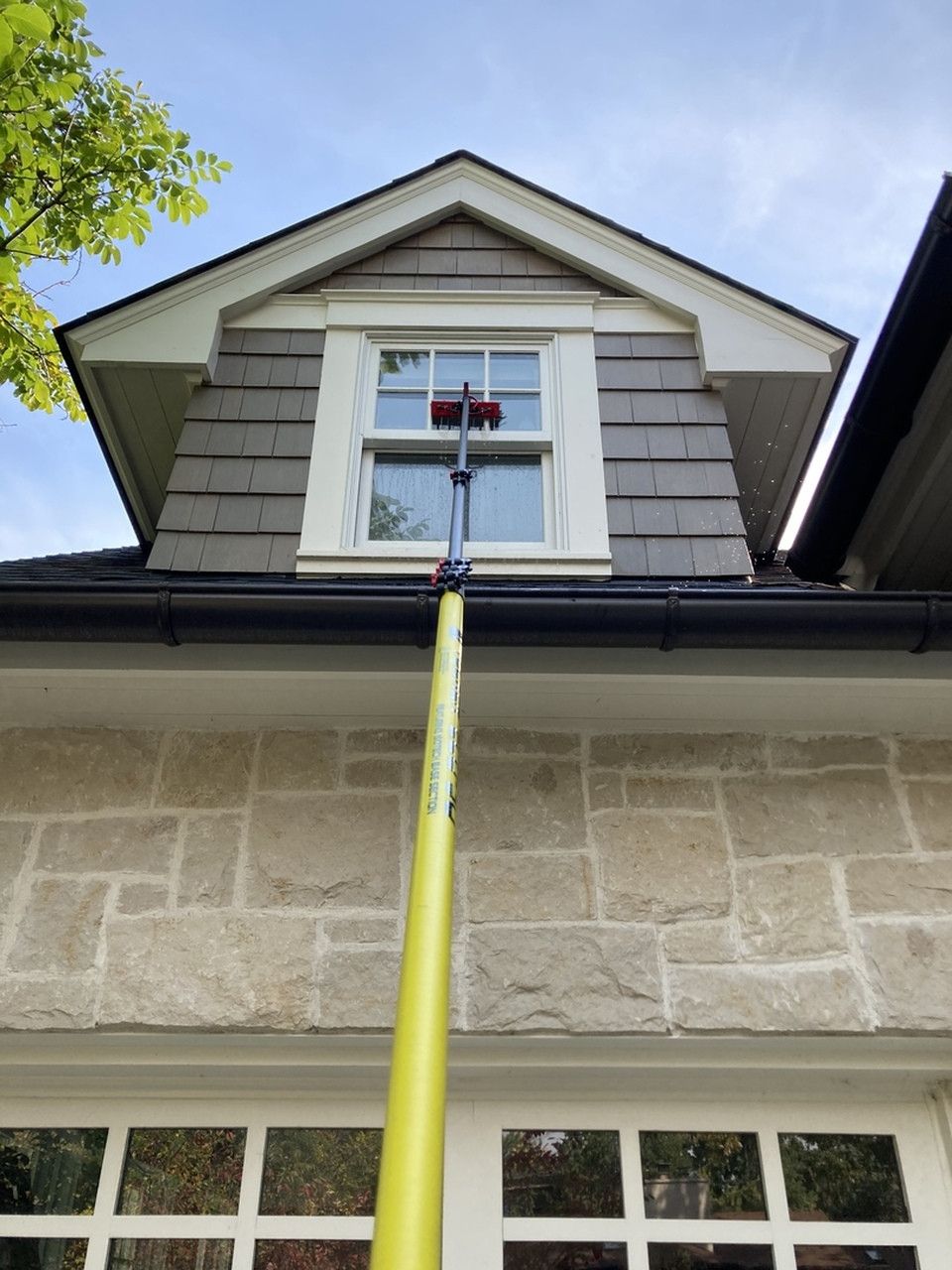 A yellow pole is hanging from the roof of a house.