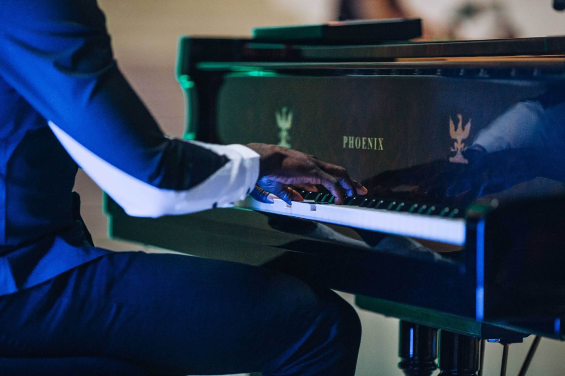 Pianist in a dark suit plays a black grand piano with a
