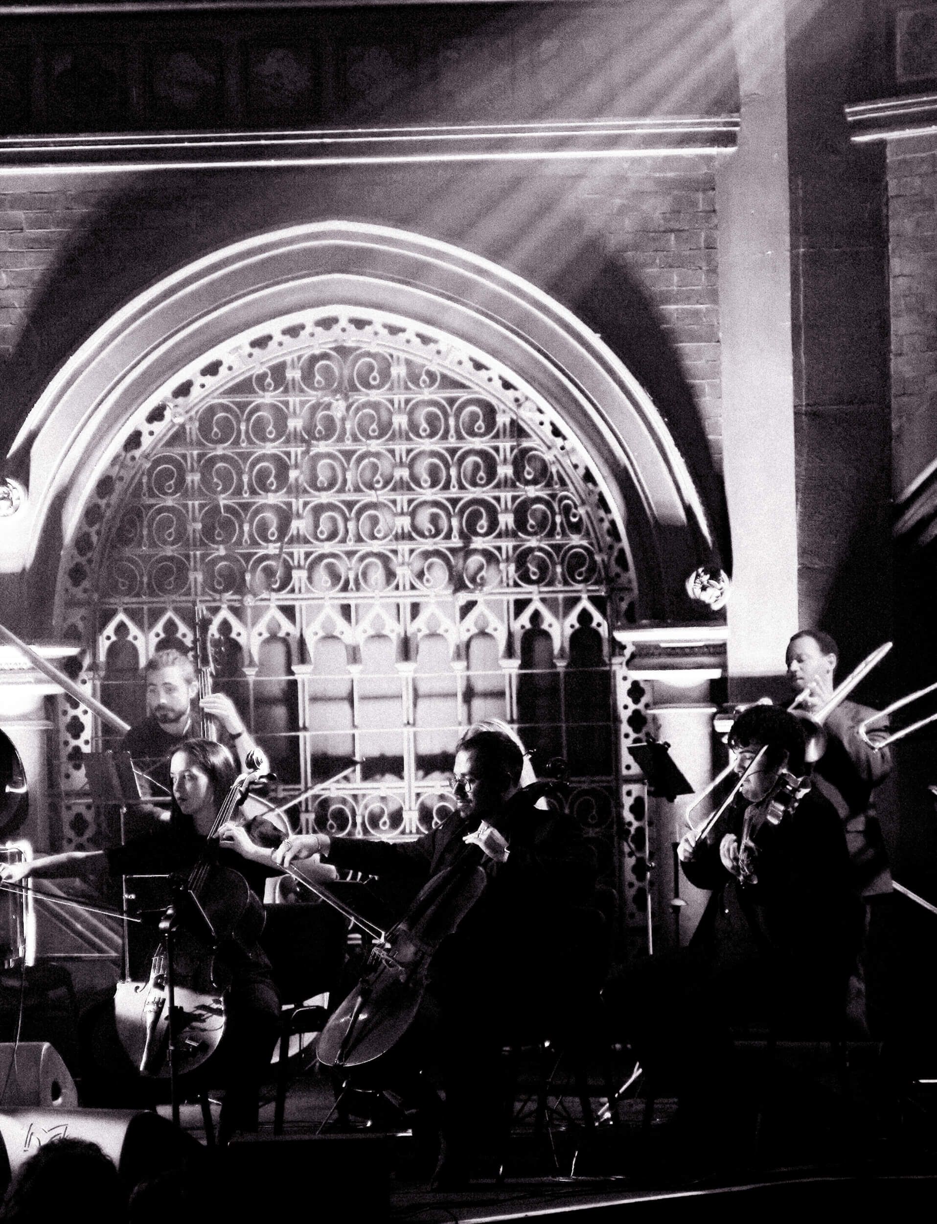 String quartet performing on stage in a church, lit by spotlights.