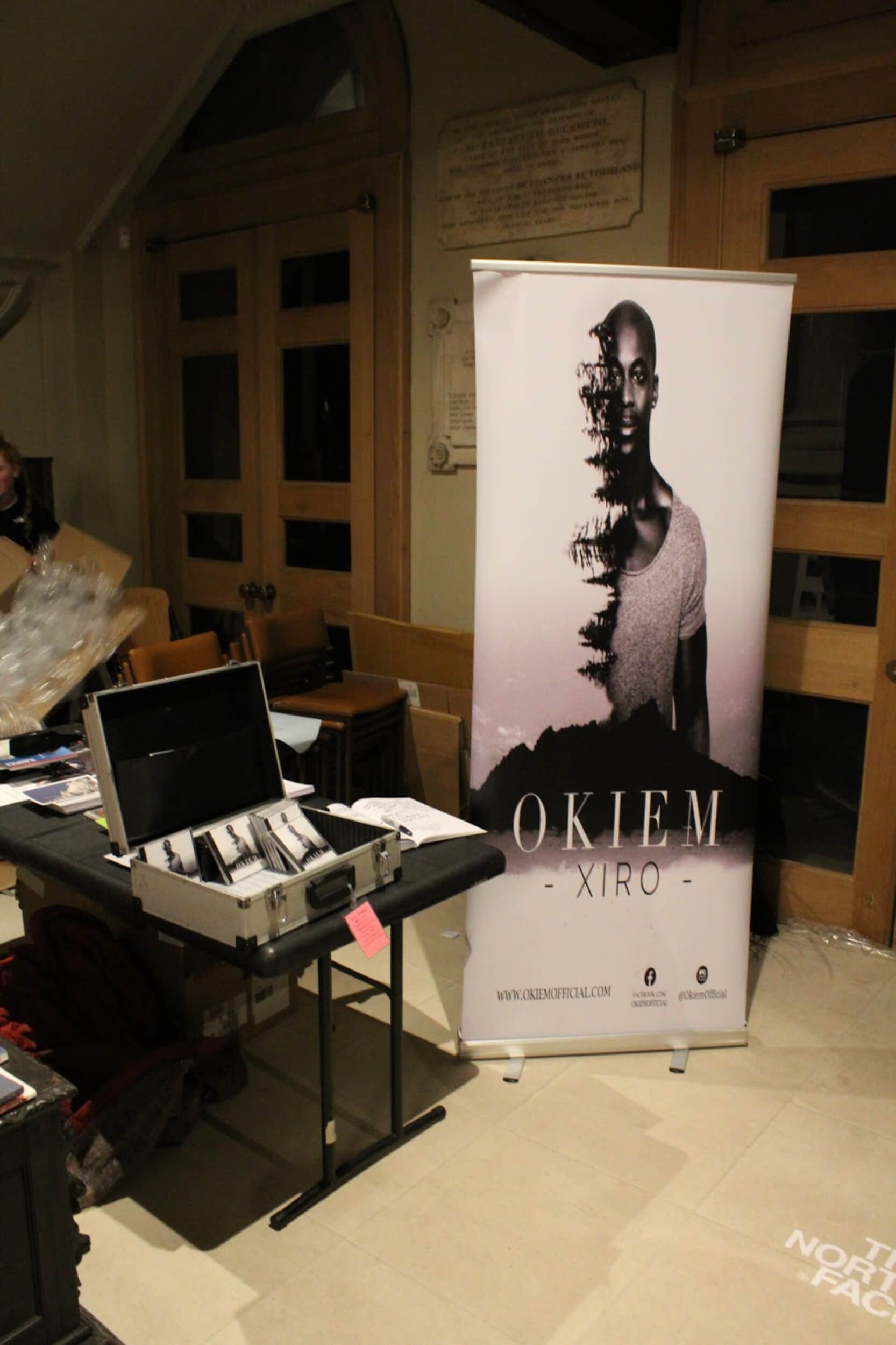 Display stand with art; case with items on table in interior space with door.