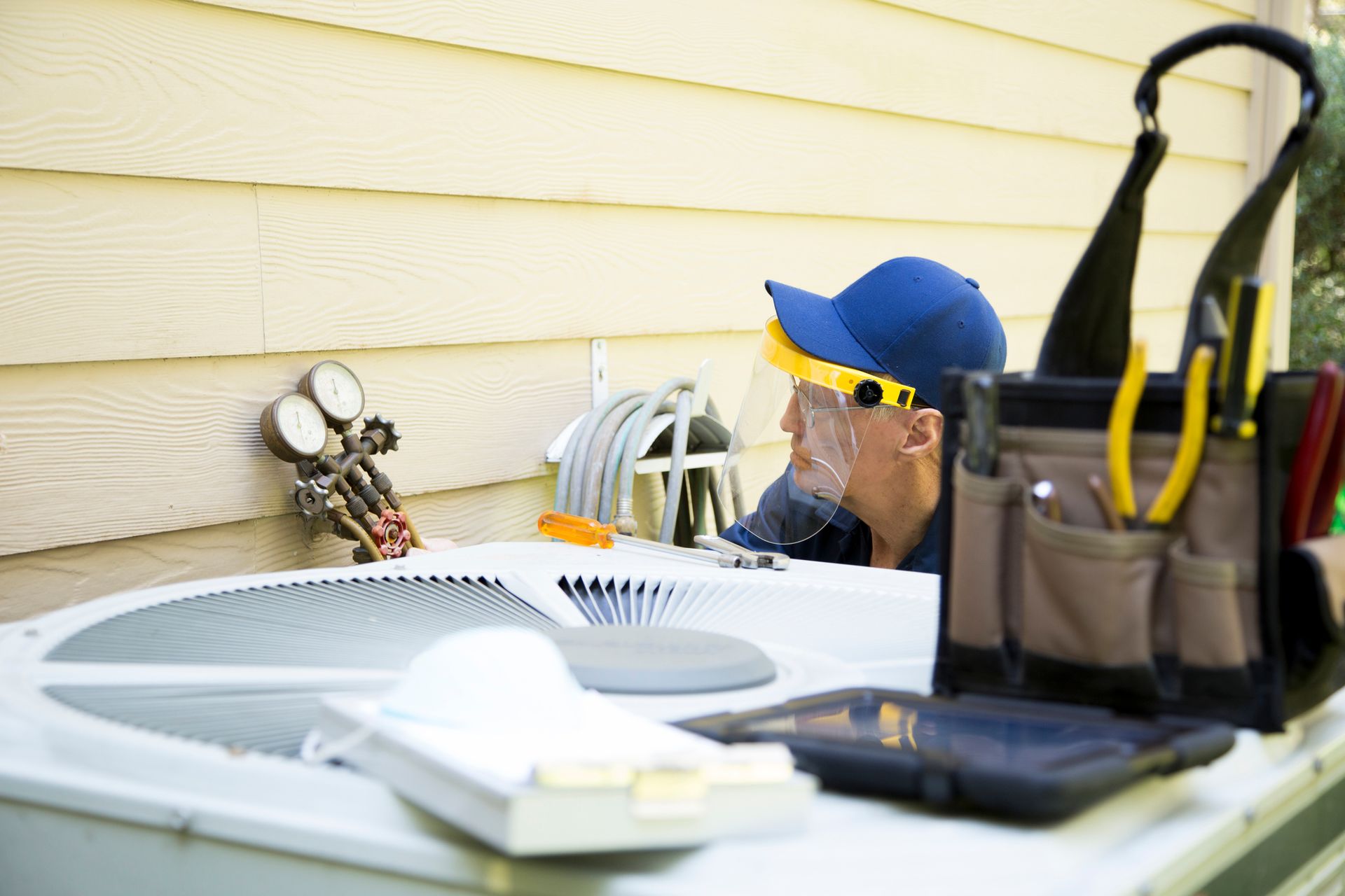 HVAC technician inspecting an outdoor air conditioning condenser unit at a North Texas home.
