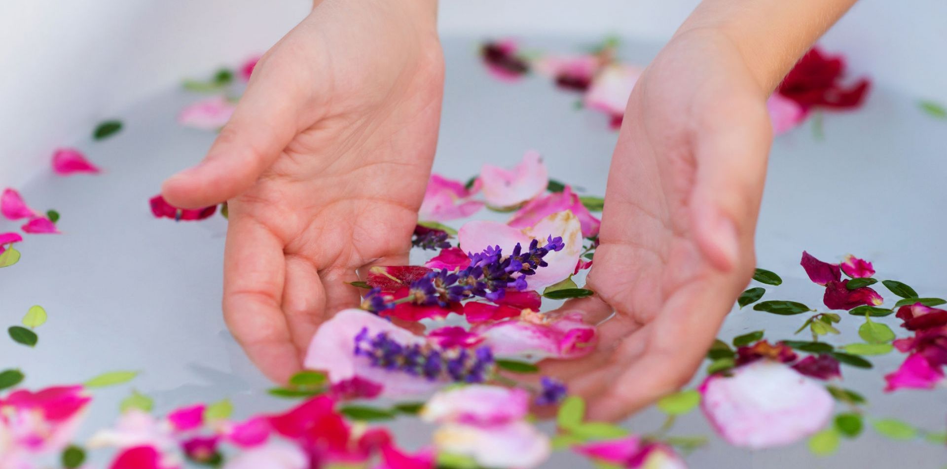 A woman is holding flowers in her hands in a bathtub.