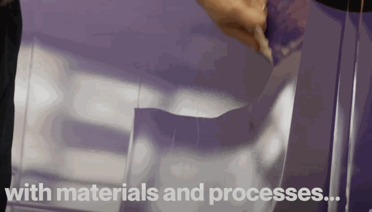 A person begins peeling back a section of reflective purple vinyl as part of a vehicle wrap installation.