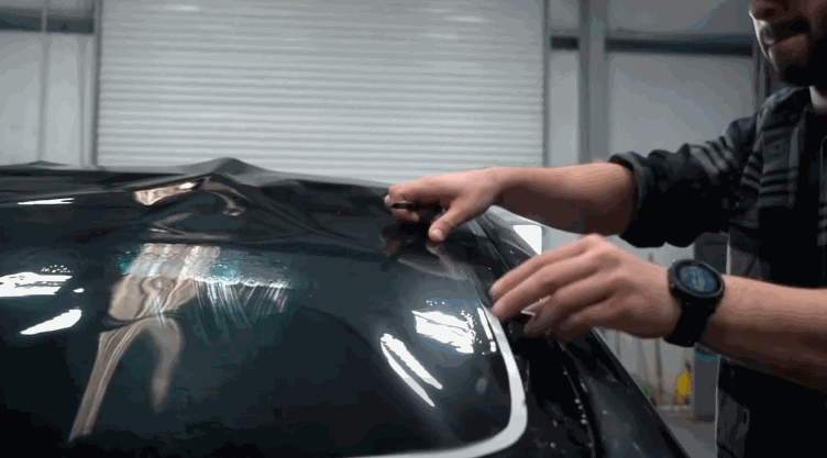 A technician applies window tinting on a vehicle, ensuring a perfect finish.
