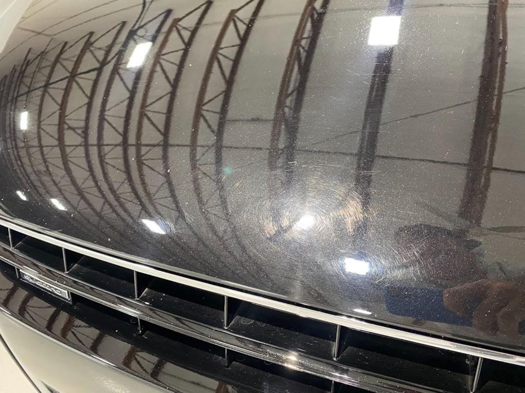 A close up of a car hood with a reflection of a building in it.