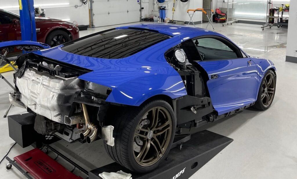 A blue sports car is sitting on top of a ramp in a garage.