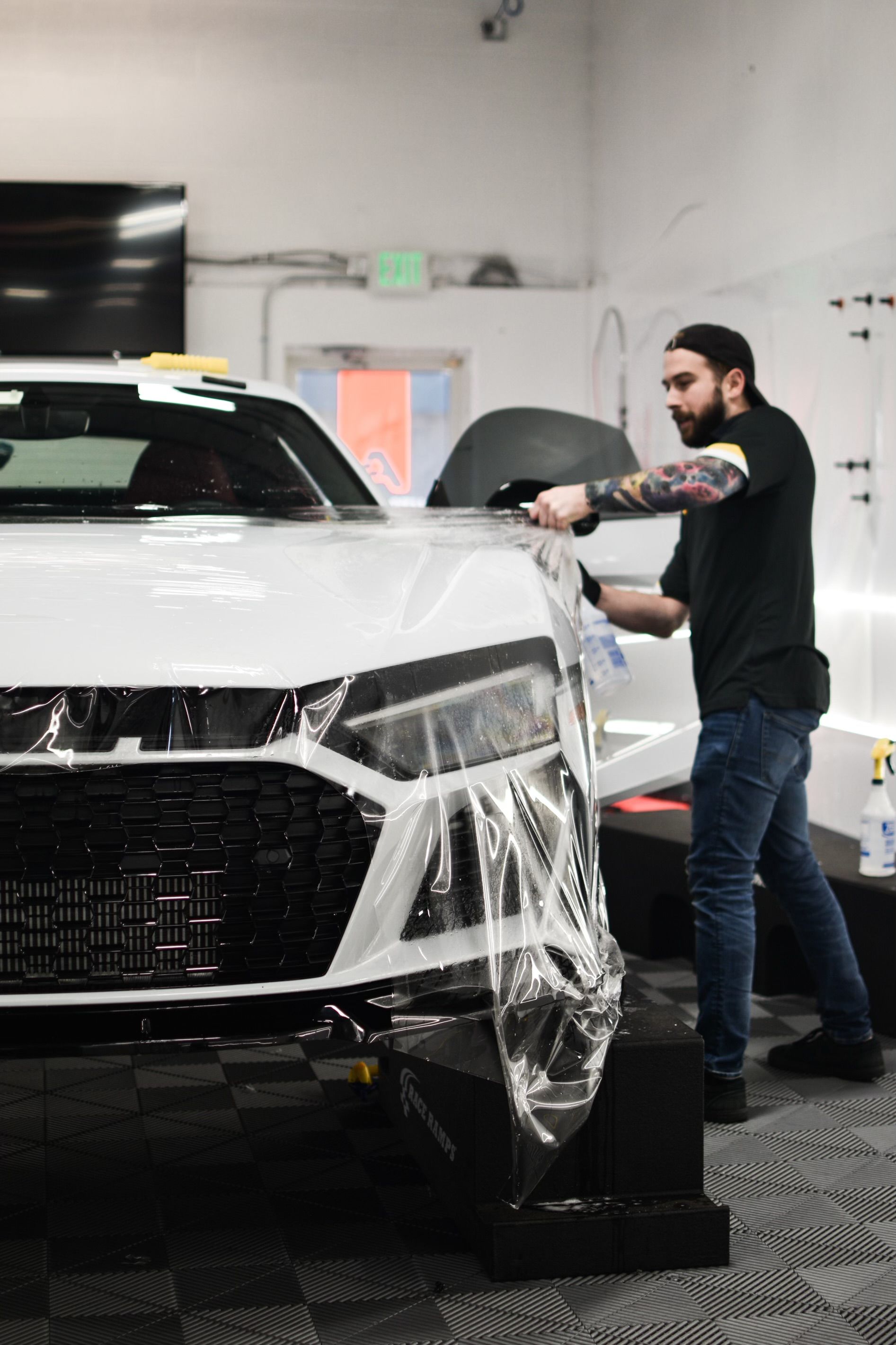 A person is applying protective film to the hood of a car.