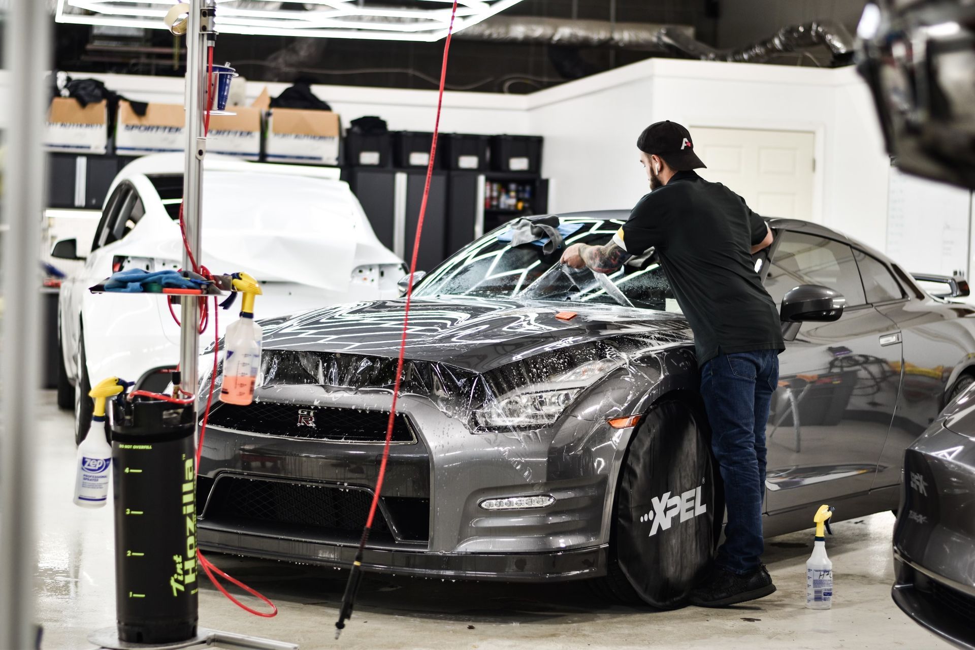 A man is applying a protective film to the side mirror of a car.