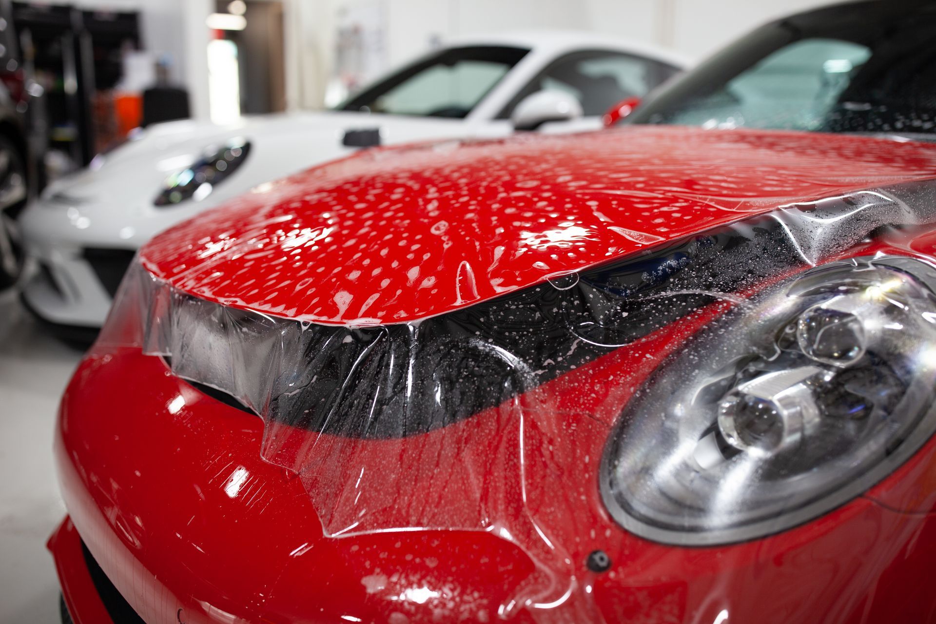 A man is applying protective film to the hood of a car.