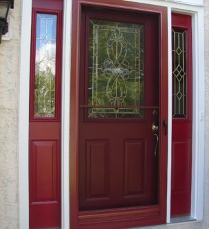 A red door with a stained glass window is on a house.