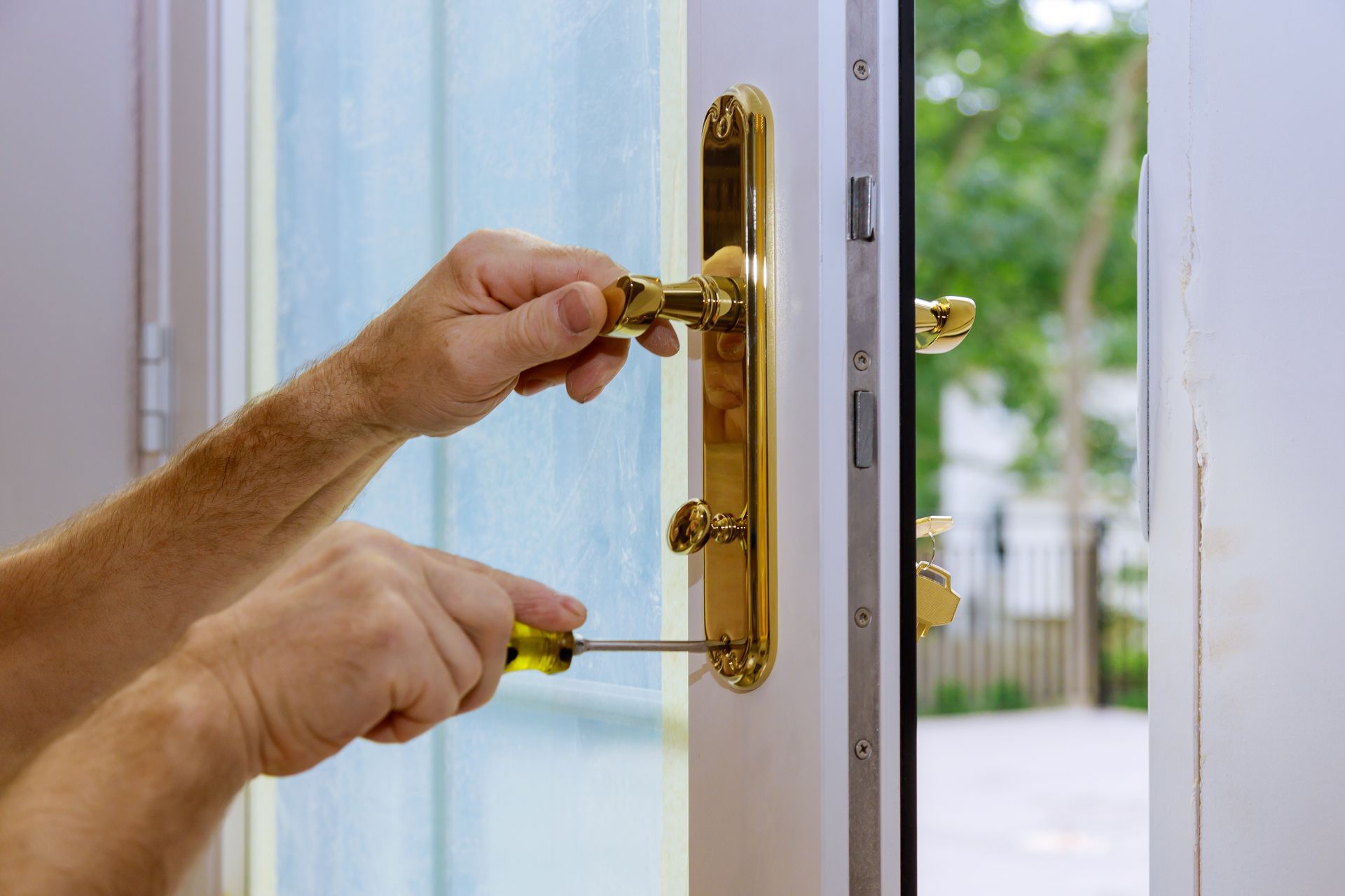 Close-up of hands replacing a white door with gold fixtures