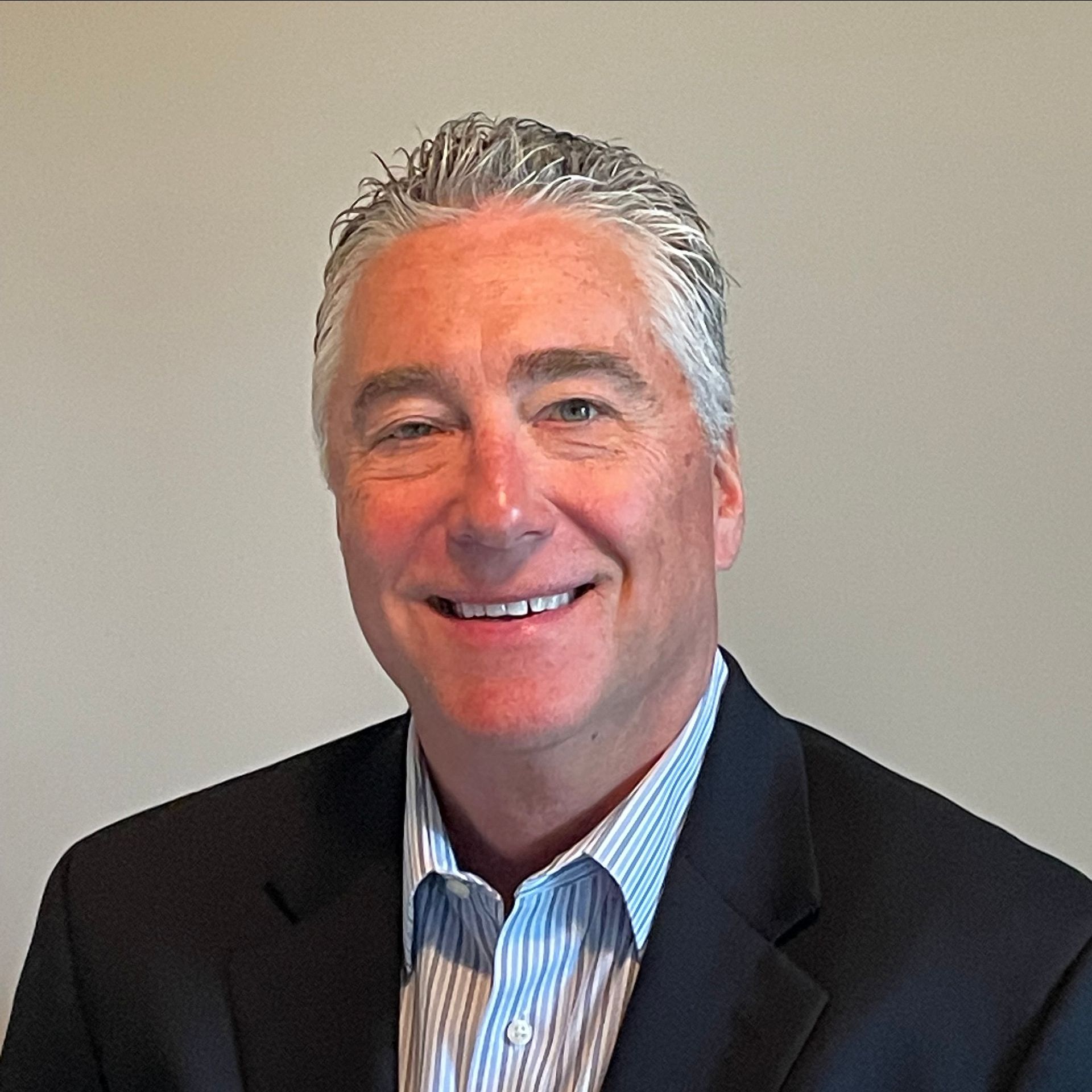 A man in a suit and striped shirt is smiling for the camera