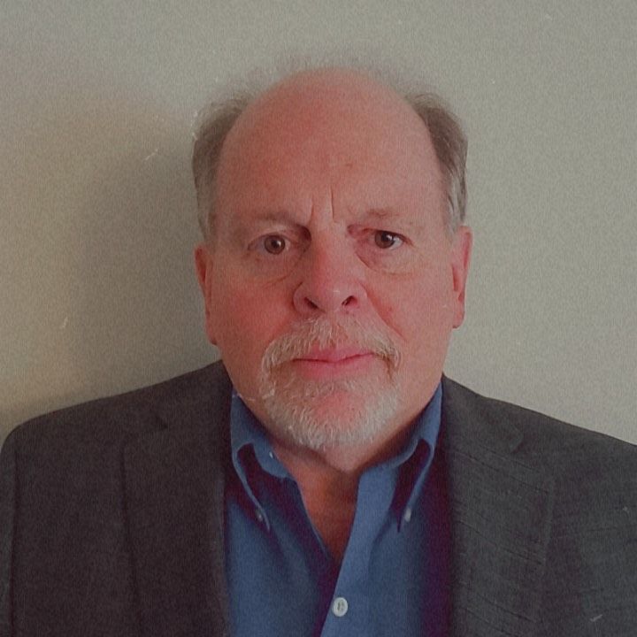 A man in a suit and striped shirt is smiling for the camera