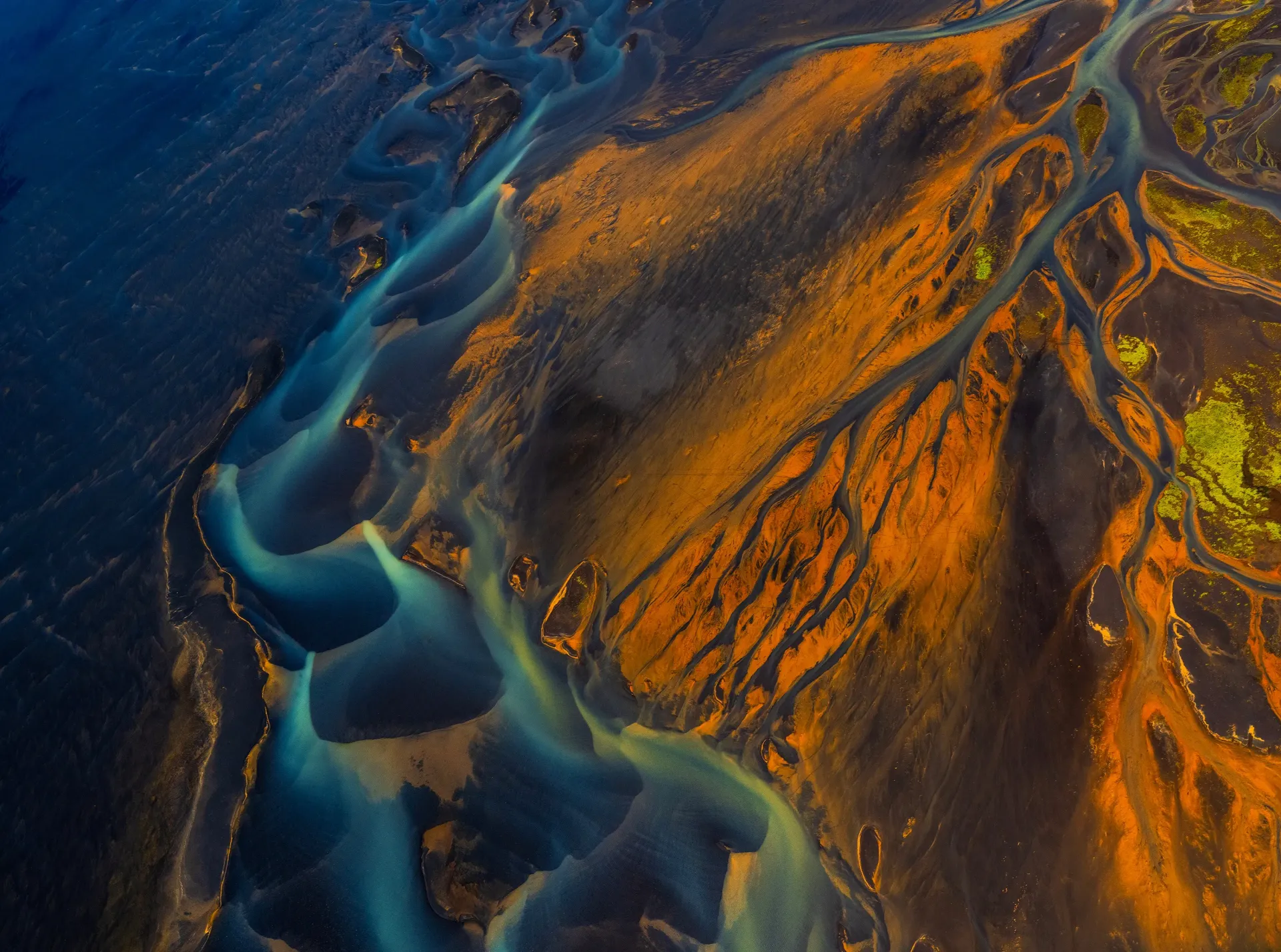 Aerial view of a blue river winding through an orange rocky landscape
