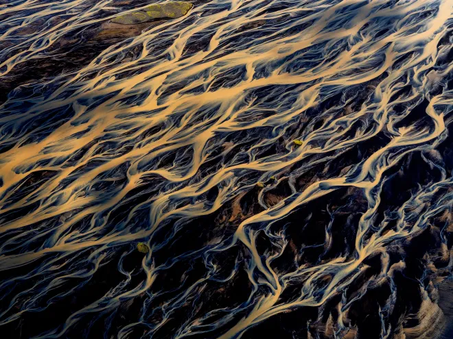 Abstract dark water with golden ripples and streaks flowing across the surface
