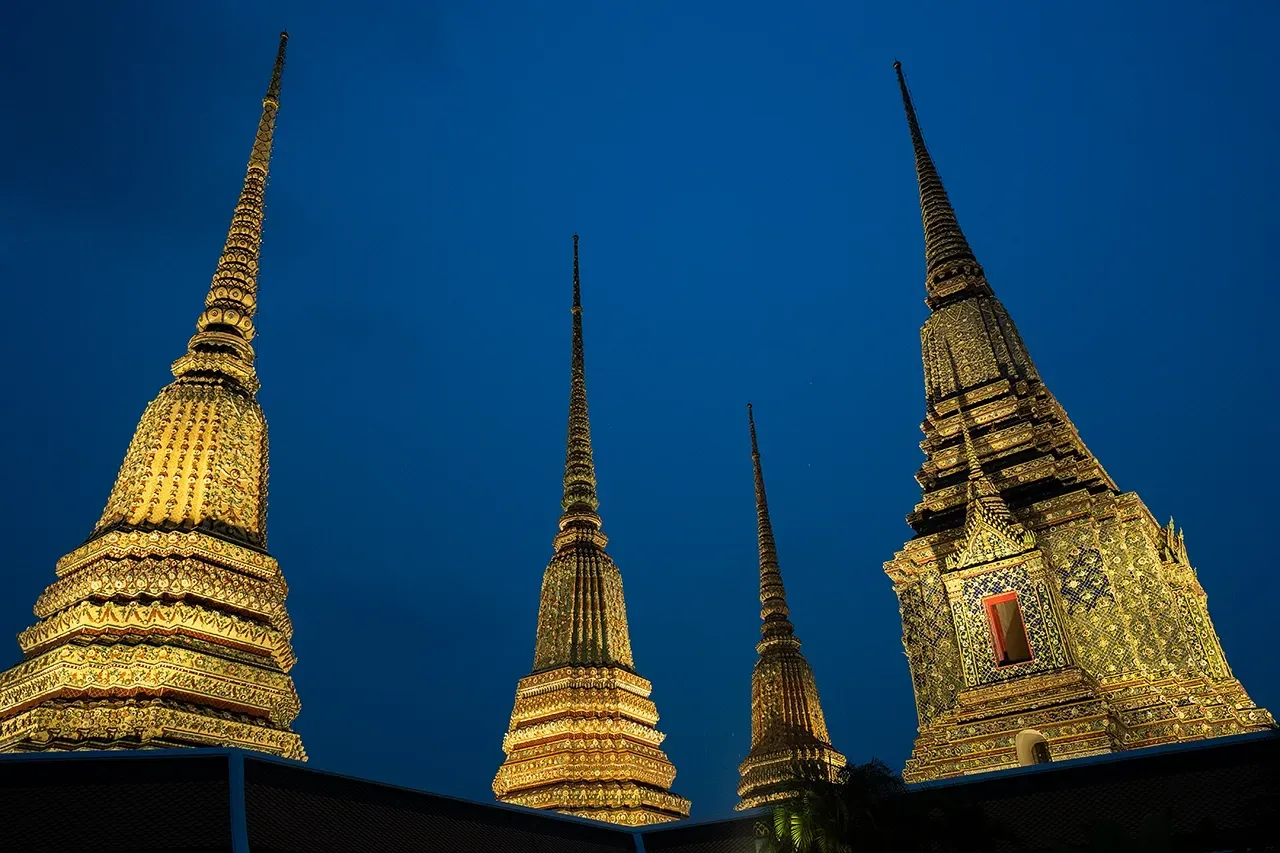 Golden temple spires lit at night against a deep blue sky