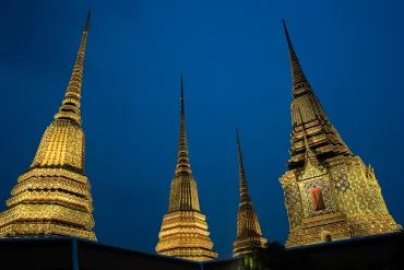 Illuminated golden temple spires at night against a deep blue sky