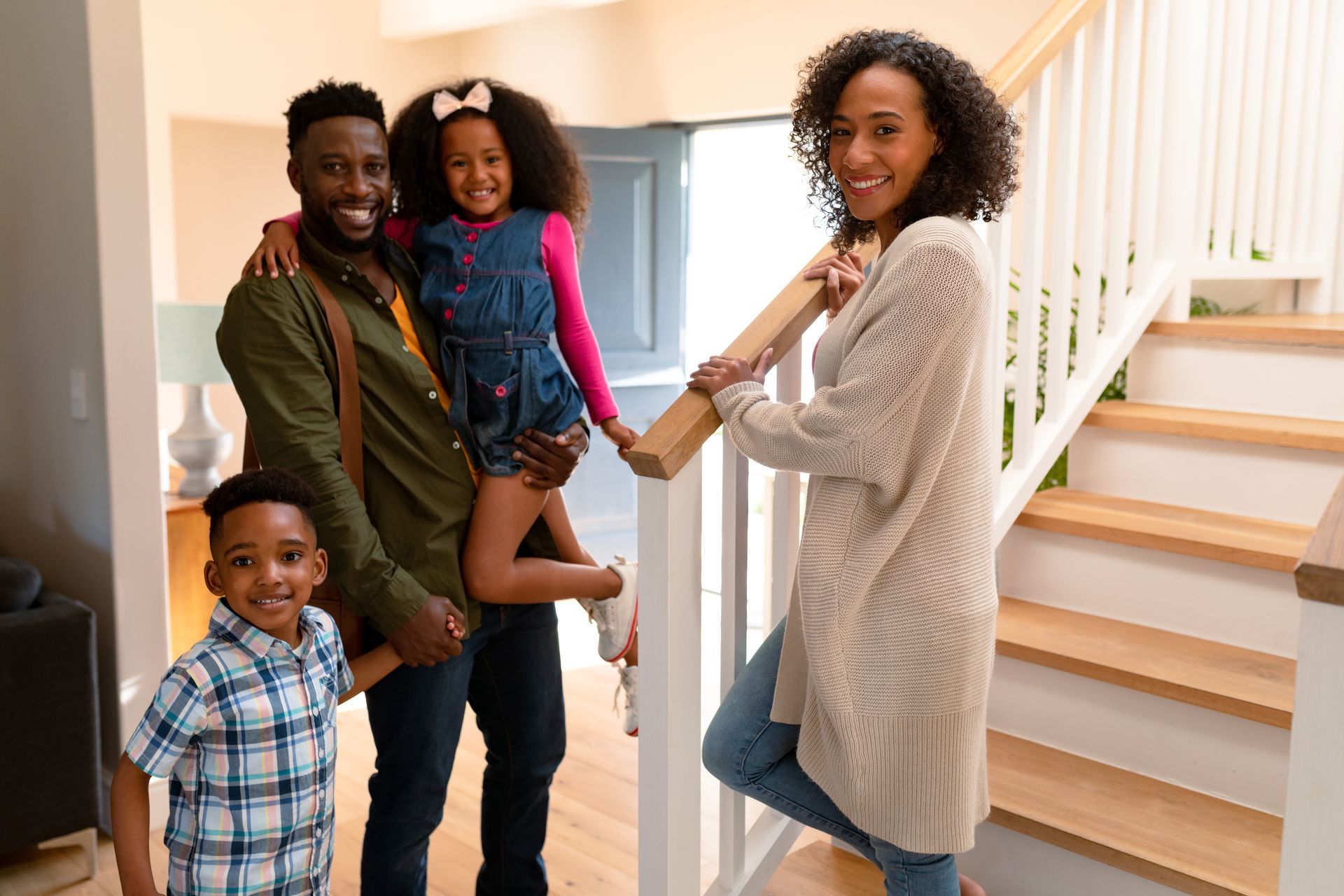 A family is standing on a set of stairs in their home.