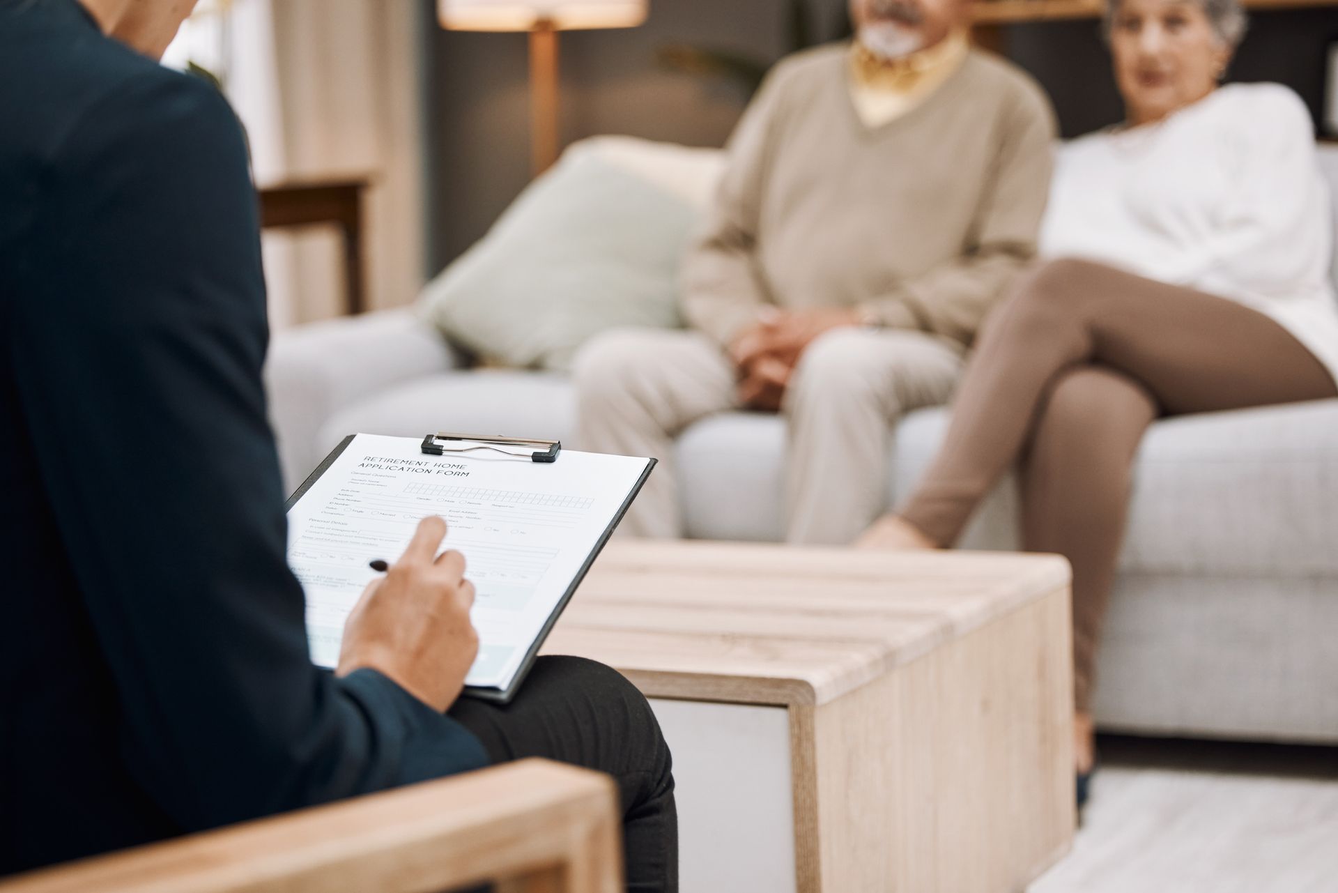 A man is sitting in a chair with a clipboard in front of a couple sitting on a couch.