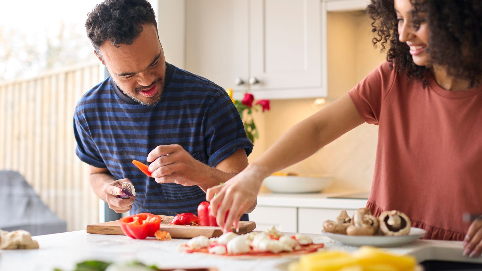 A man and a woman are preparing food in a kitchen.