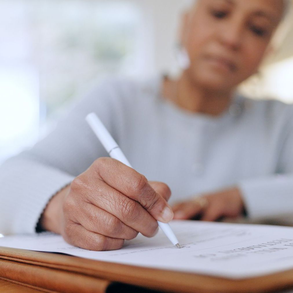 A woman is writing on a piece of paper with a pen.