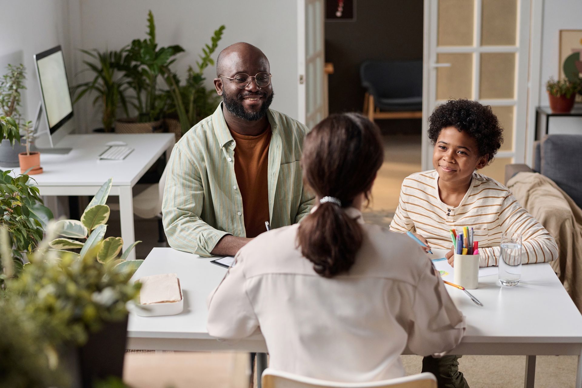 A man and two children are sitting at a table talking to a woman.