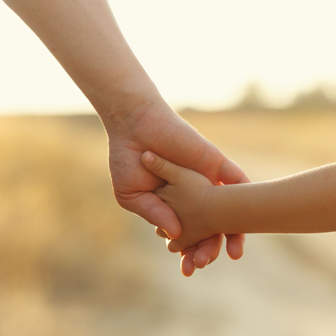 A woman is holding a child 's hand in a field.