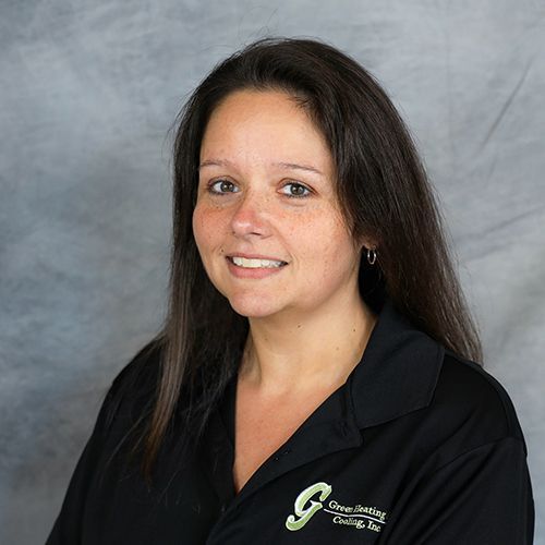 Woman smiling, wearing black shirt with logo, posing for a headshot in front of gray backdrop.