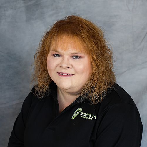 Woman with red hair smiling, wearing a black shirt with a company logo.
