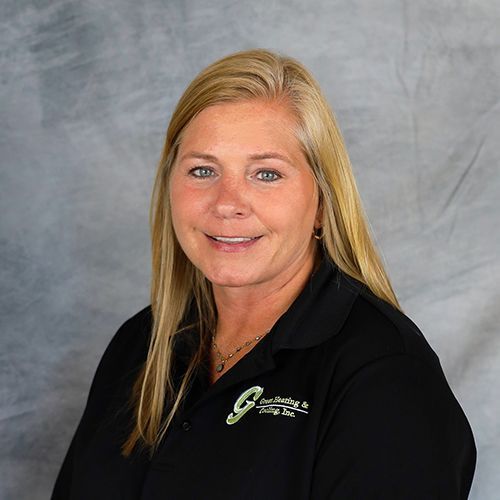 Blonde woman smiles, wearing a black shirt with a company logo on a gray backdrop.