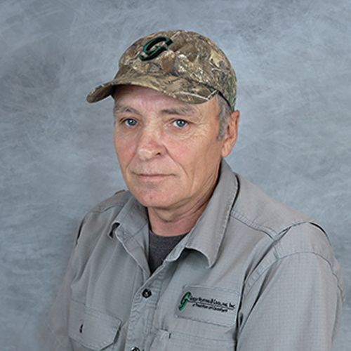 Man in camouflage hat and grey shirt, looking at the camera.