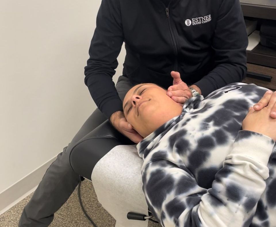 A woman is laying on a table getting a massage from a doctor.