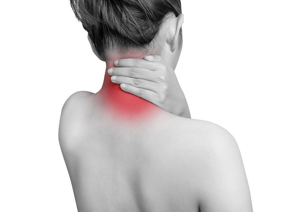 A woman is holding her neck in pain and has a red spot on her neck.