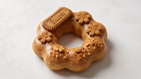 Glazed donut topped with a biscuit and flower-shaped cookies on a white background