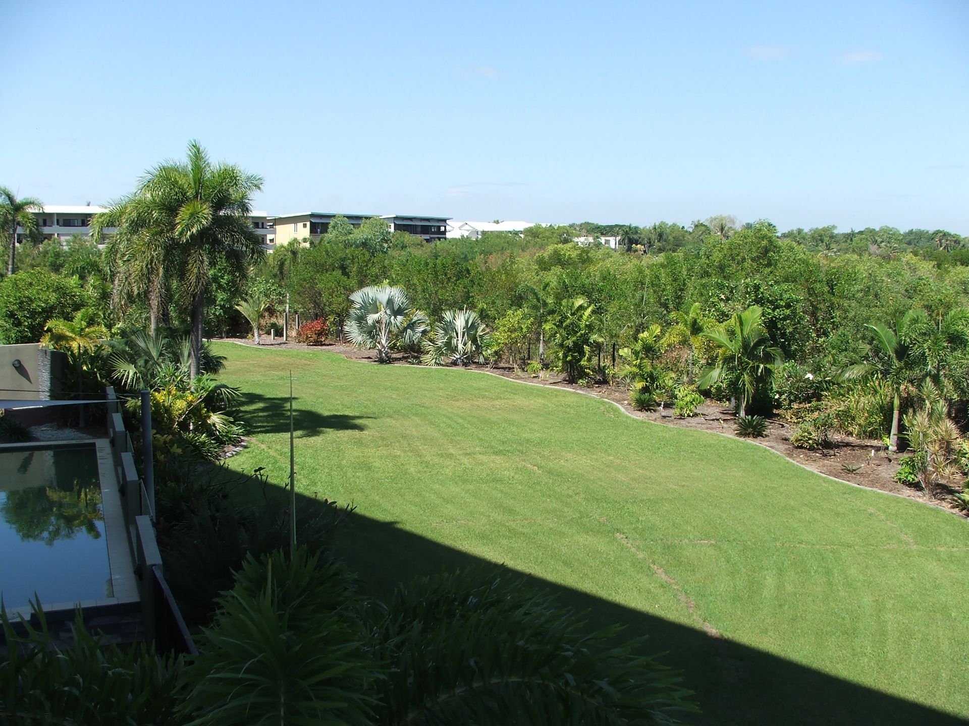 A lush green field with trees and buildings in the background