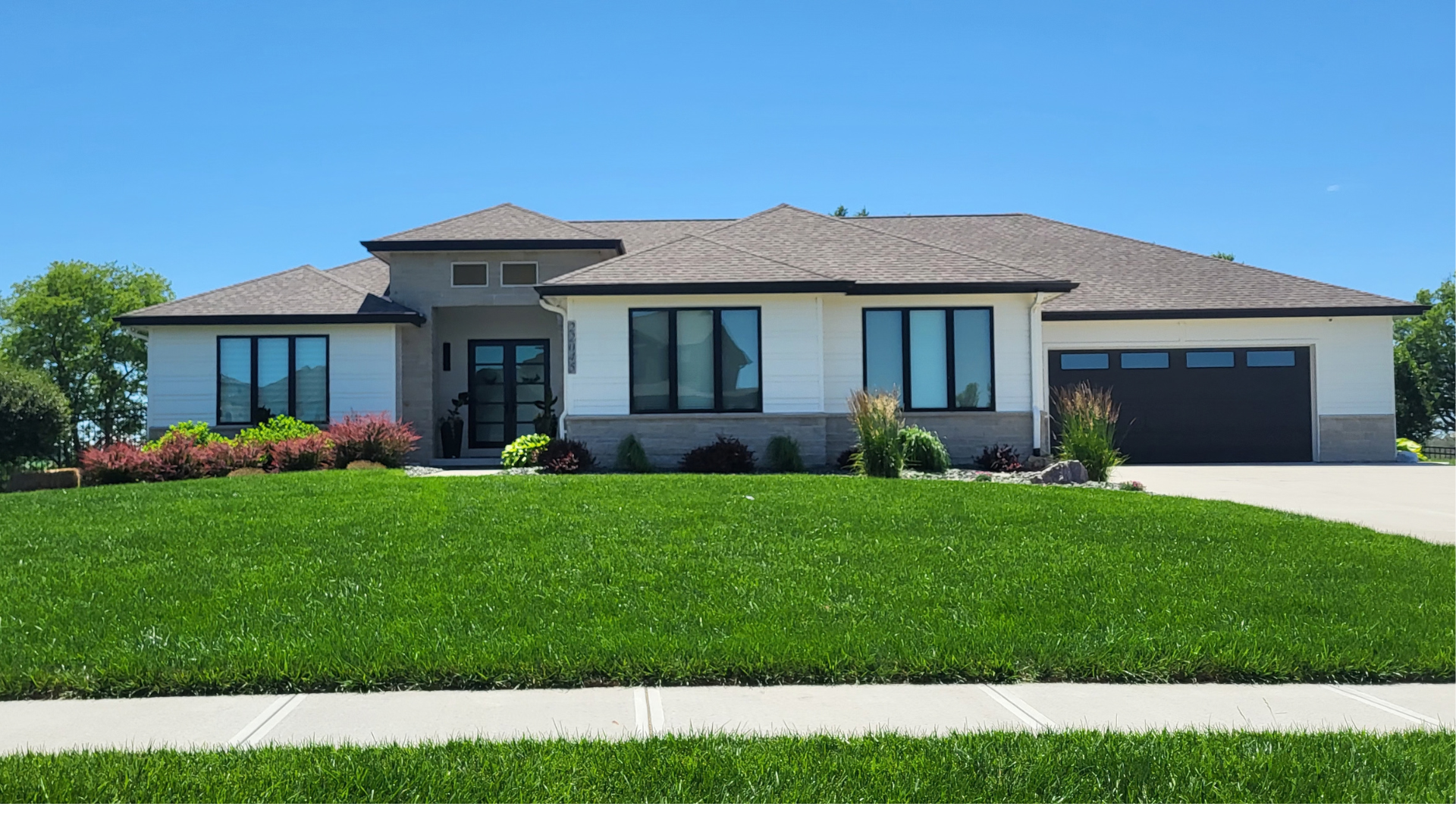 Suburban two-story house with beige siding, red front door, white garage, and a concrete driveway