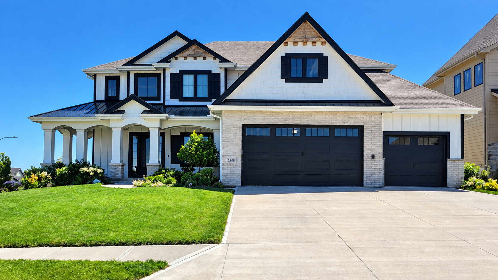 Large two-story suburban house with white siding, black trim, a three-car garage, and a green lawn