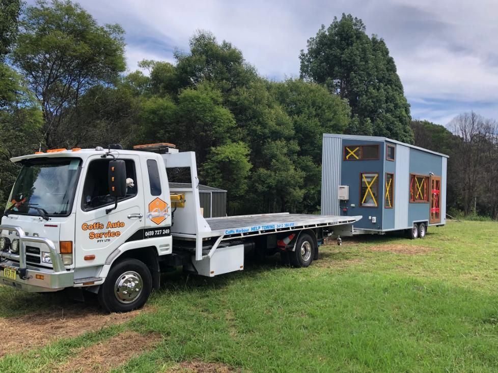 A Tow Truck With a Trailer Attached to It is Parked in a Grassy Field — Coffs Tow Trucks In North Boambee Valley, NSW