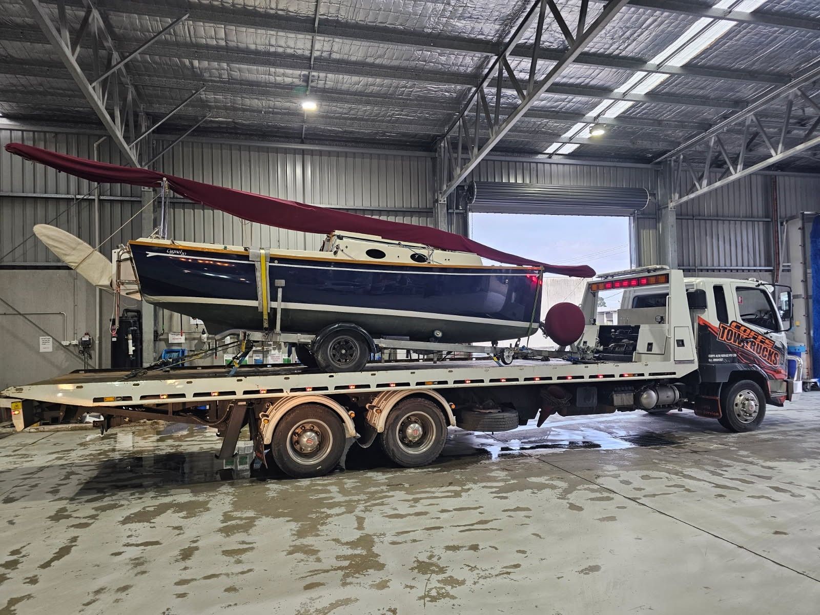 Small Sailboat On A Flatbed Trailer Inside A Warehouse  — Coffs Tow Trucks In North Boambee Valley, NSW