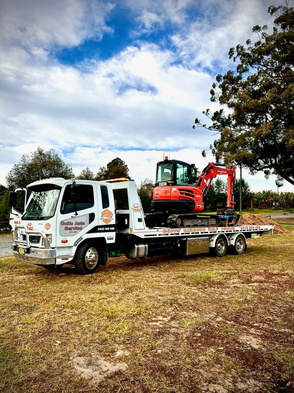 White Flatbed Tow Truck Carrying A Red Mini Excavator — Coffs Tow Trucks In Macksville, NSW