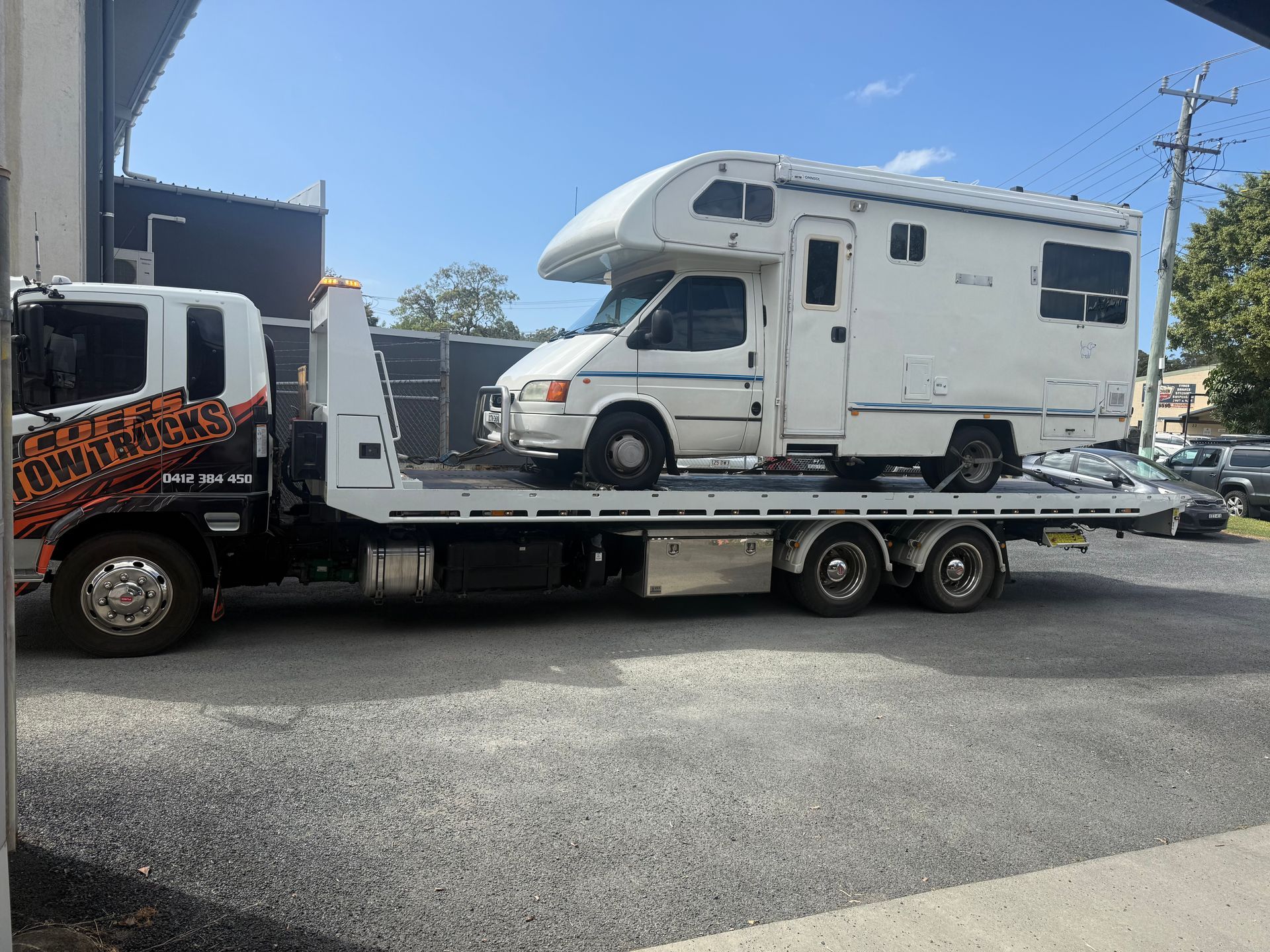 White Rv On A Flatbed Tow Truck Parked Outdoors — Coffs Tow Trucks In Nambucca Heads, NSW