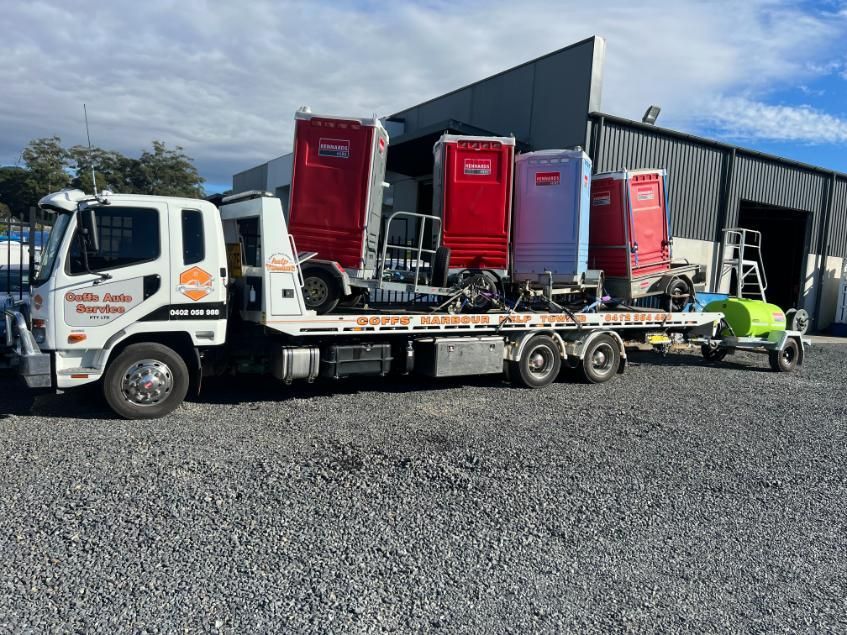 A Tow Truck is Carrying a Trailer Full of Portable Toilets — Coffs Tow Trucks In Woolgoolga, NSW