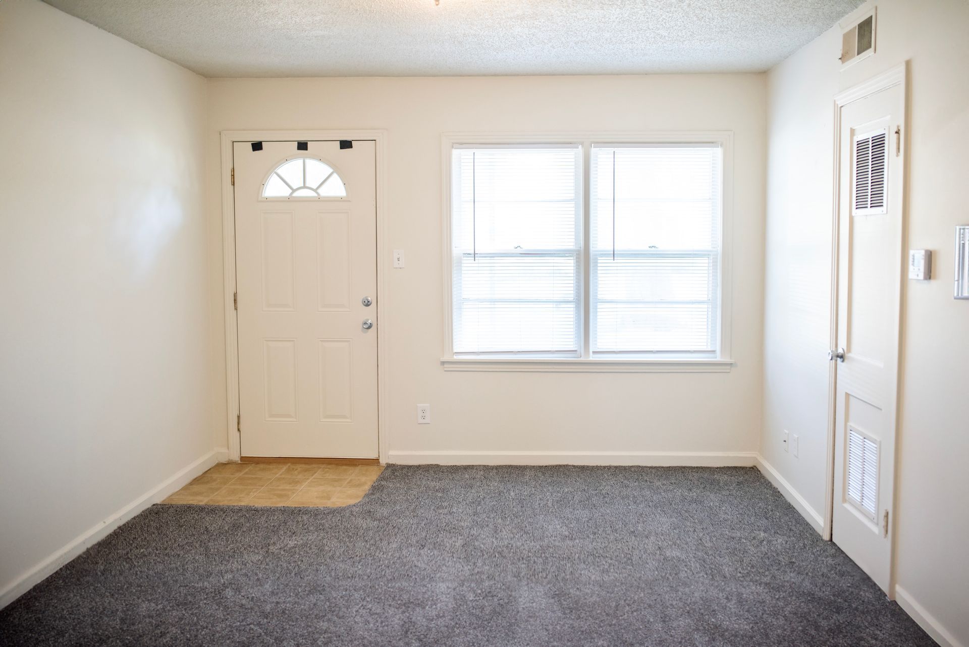 An empty living room with a door and a window.