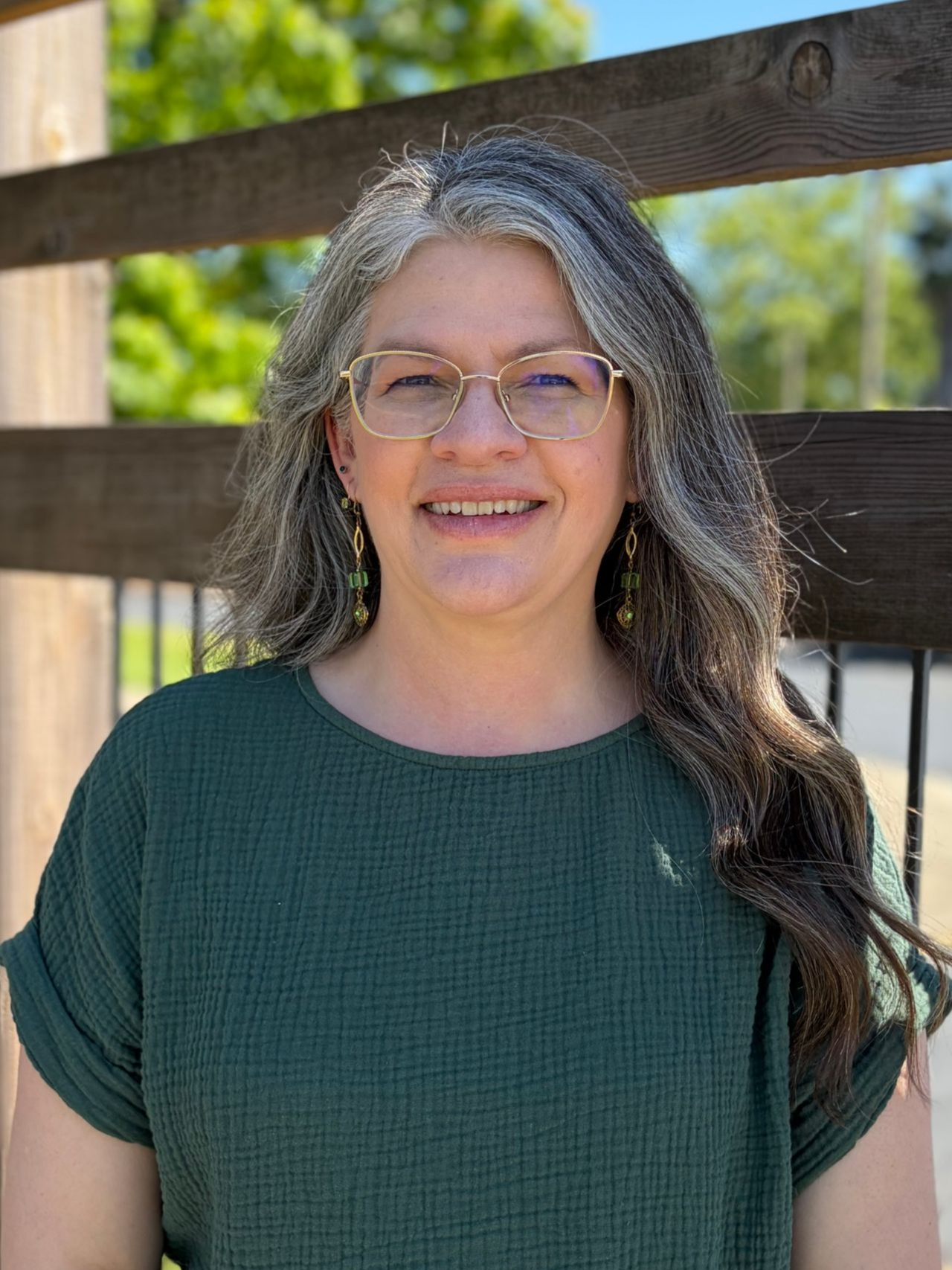 A woman wearing glasses and a red floral shirt is smiling for the camera.