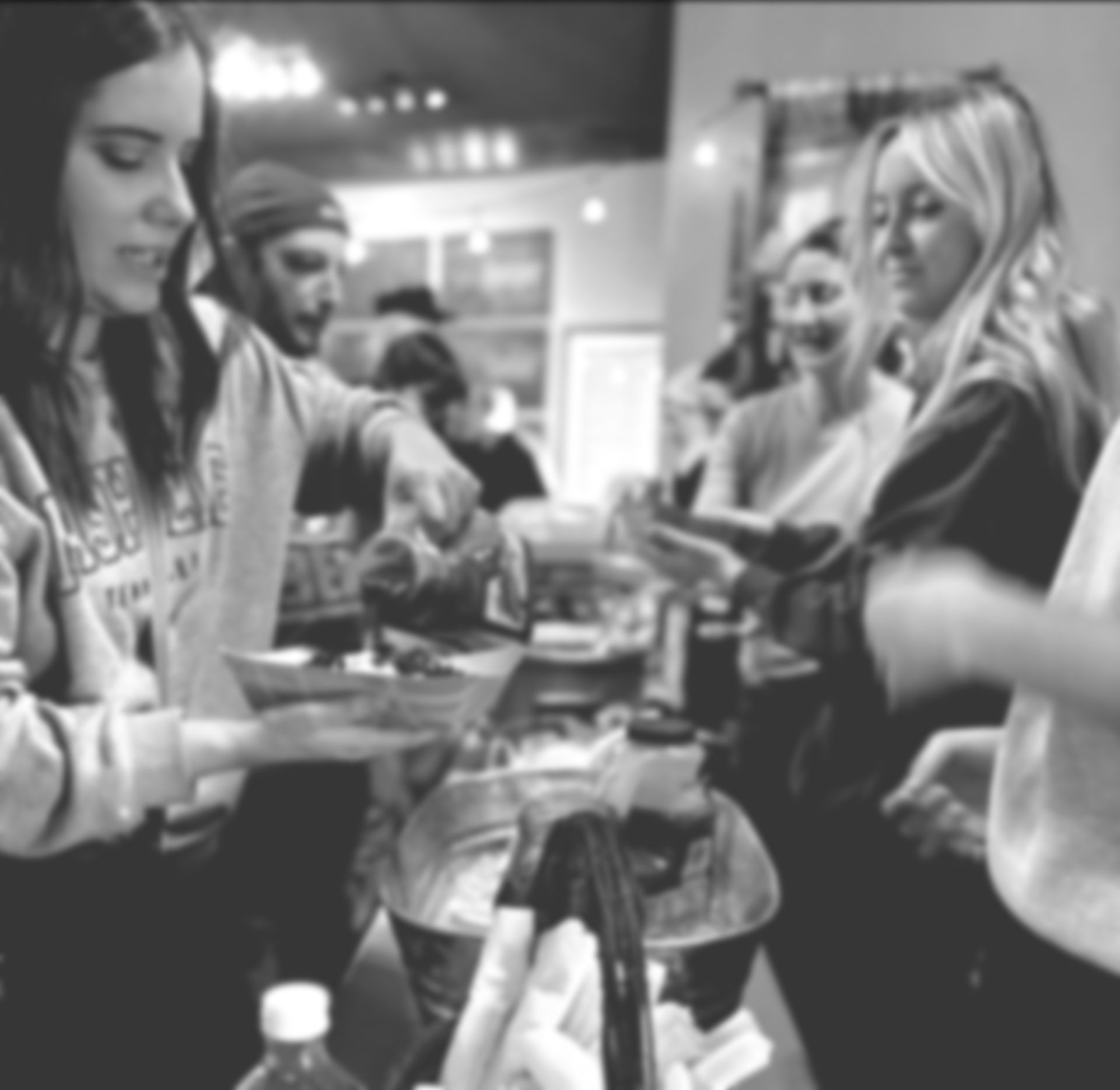 A black and white photo of a group of people standing around a table