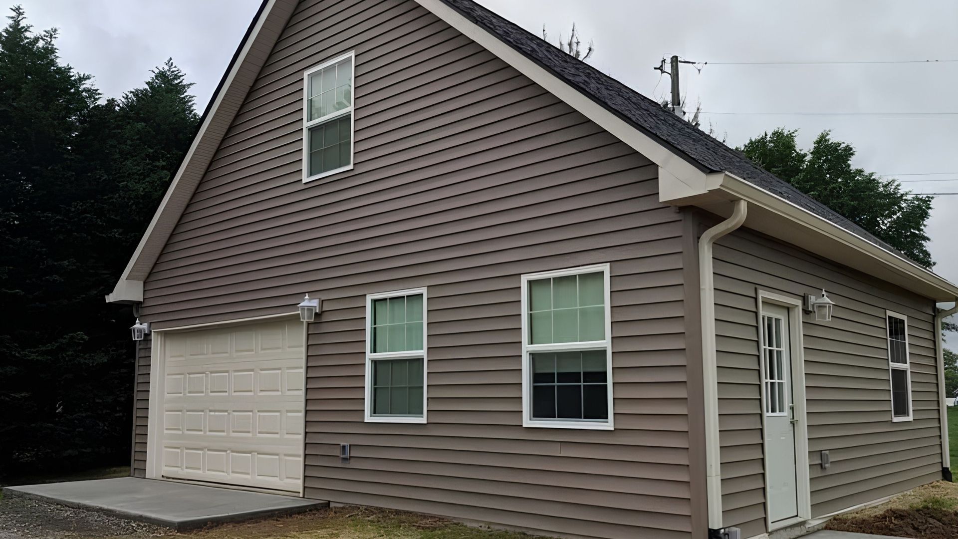 Brown two-story house with attached garage and white trim on a cloudy day