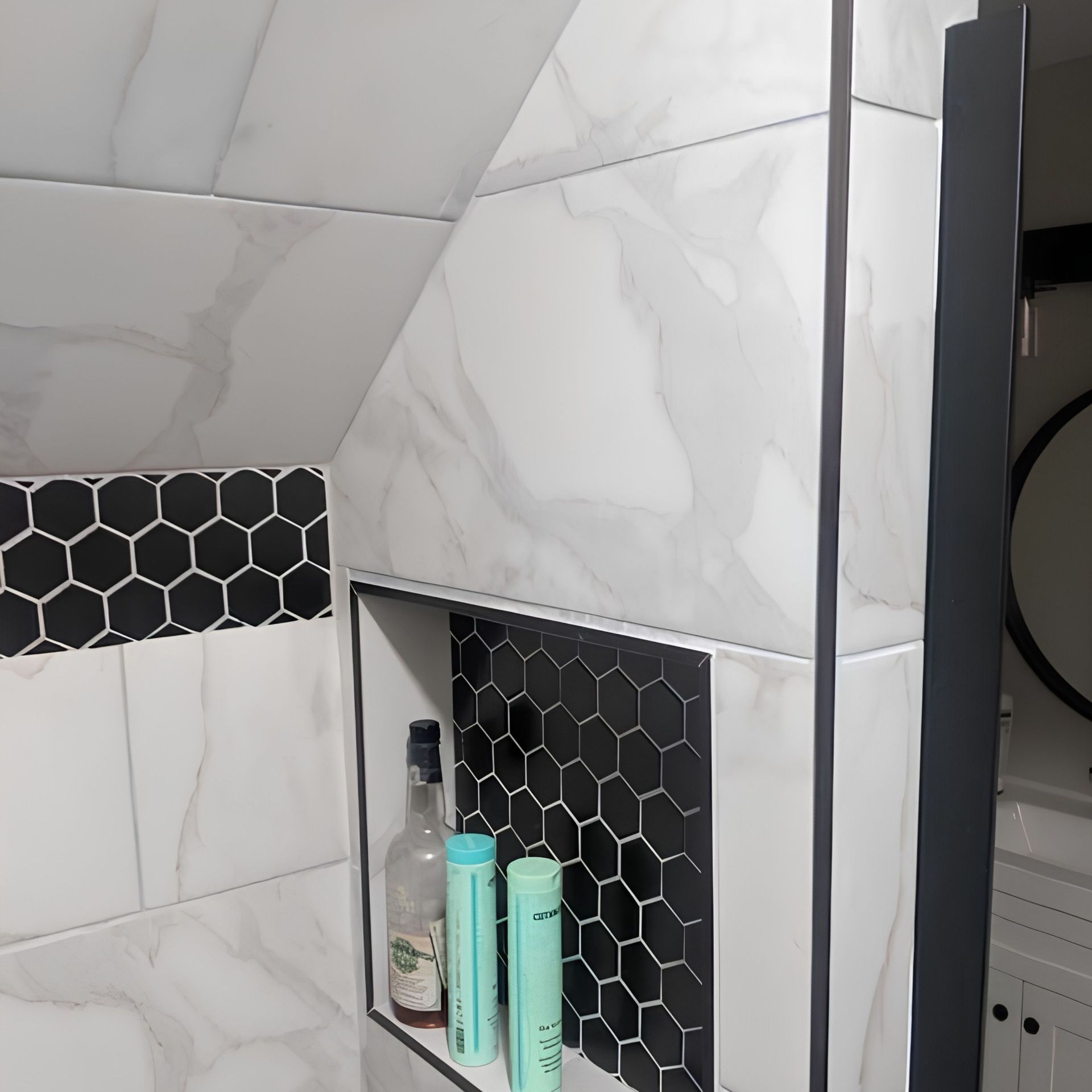 Bathroom shower niche with black hex tile and several toiletries on a shelf