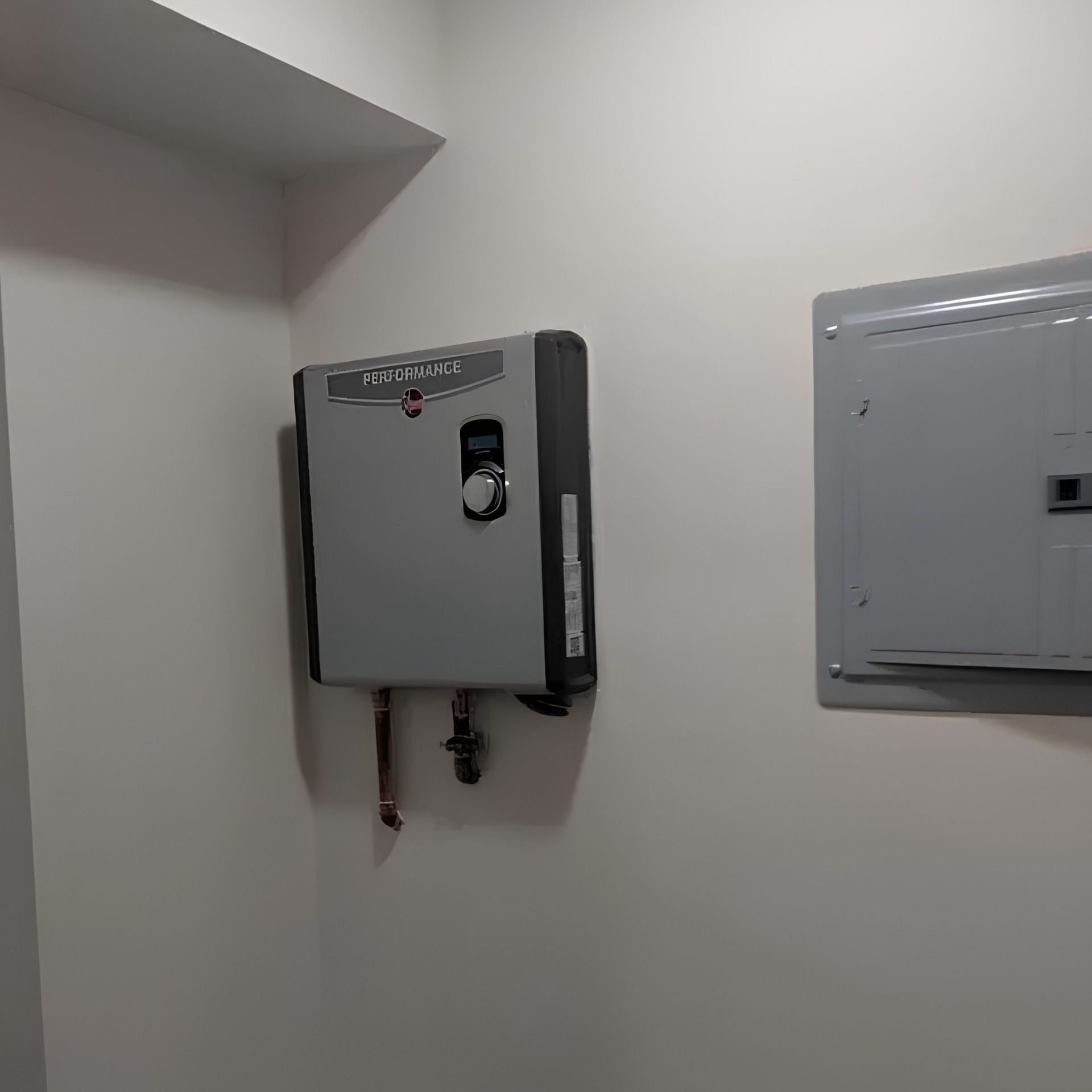 Wall-mounted gray control box and electrical panel in a plain indoor utility room