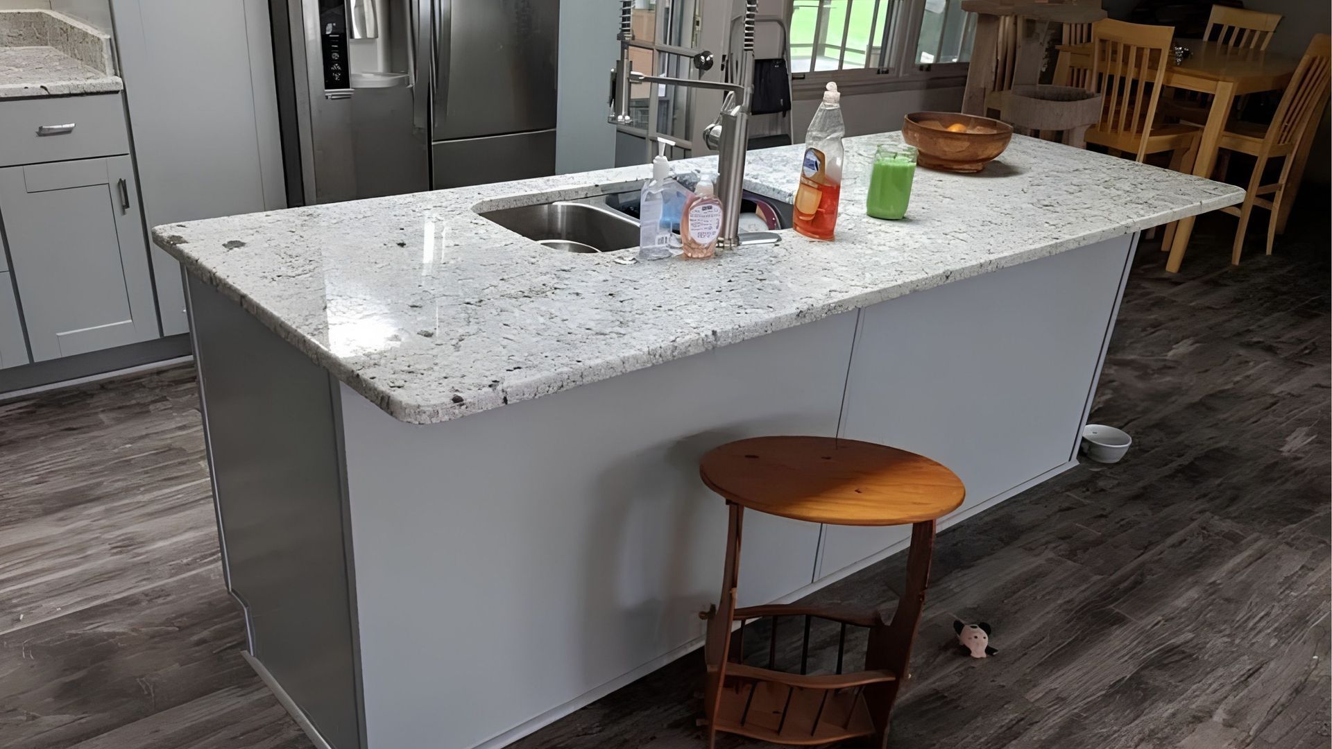 Kitchen island with granite countertop, sink, and a stool in a modern home interior